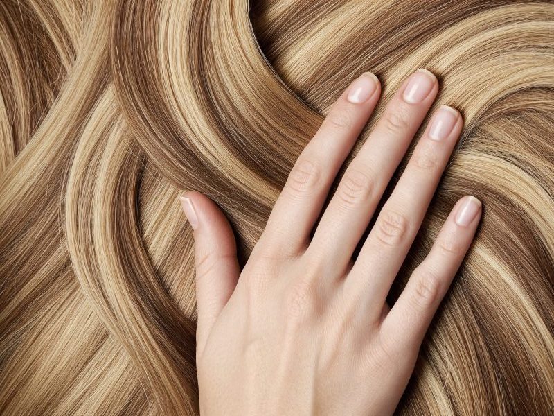hand-touching-wavy-highlighted-hair