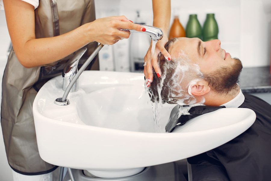 Man with a beard. Hairdresser with a client. Woman washing man's head